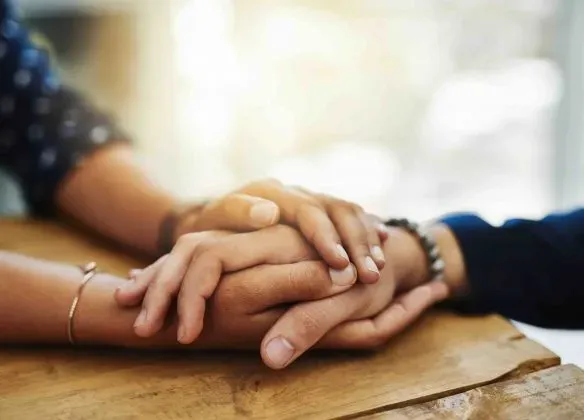 Gros plan sur deux personnes se tenant les mains en signe de soutien et de confort.